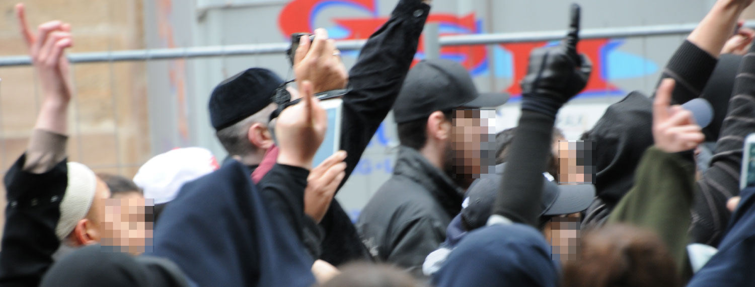 Gruppenbild: Salafistische Anhänger protestieren mit erhobenem Zeigefinger. 
