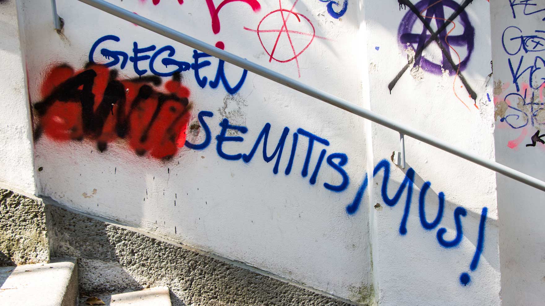 Eine Wand, auf der Gegen Semitismus steht. Mit schwarzer Farbe und roter Umrandung wurde Anti vor das Wort Semitismus gesetzt. 